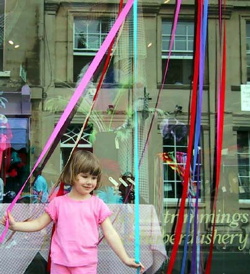 Small grild playing with ribbons in front of a haberdashers